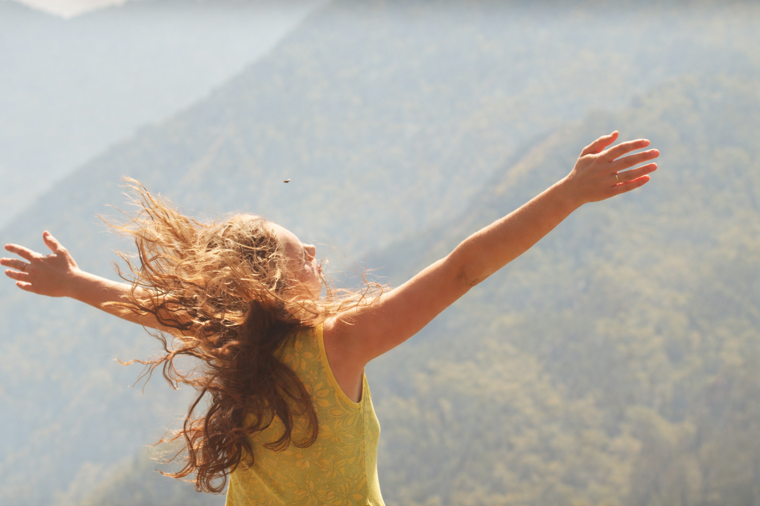Person with arms outstretched overlooking mountain landscape